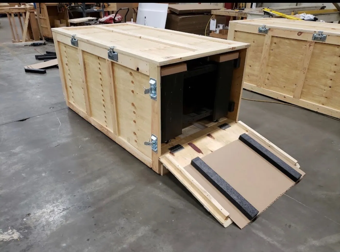 A custom wooden crate built by The Flat Rate Movers with its foam-lined ramp door open, ready for protected loading